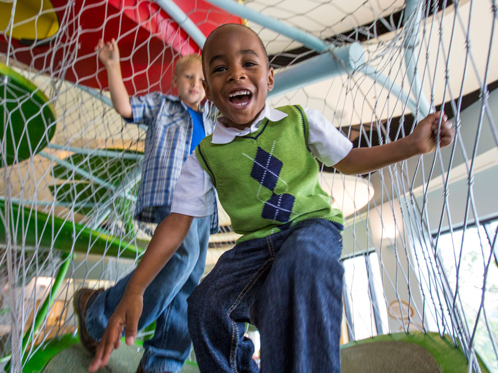 Children smiling and climbing in Playscape.